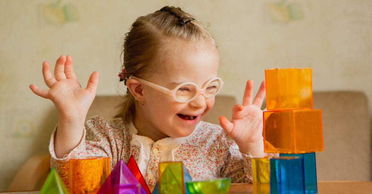 A special needs education student has fun playing with blocks while giggling